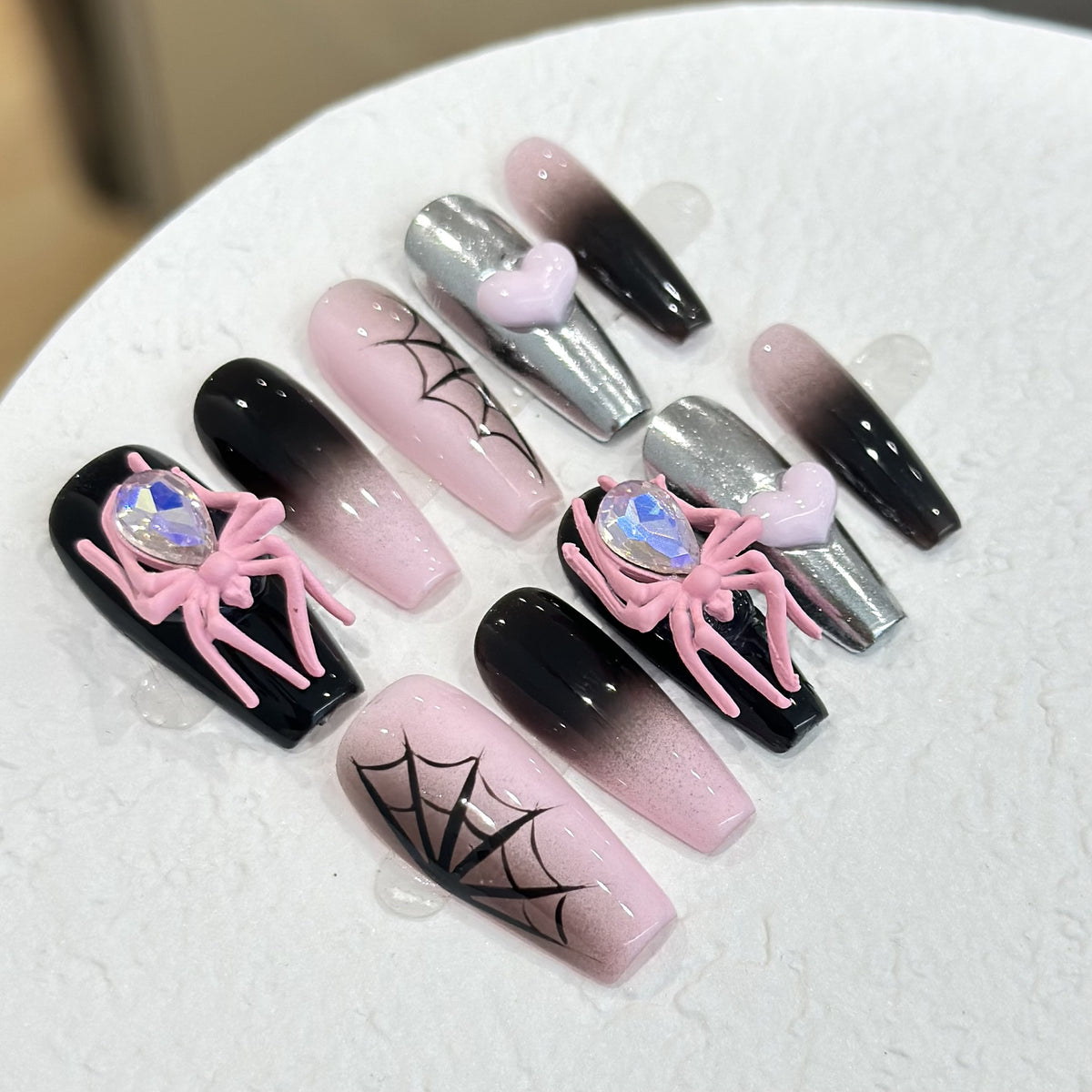 Black & Pink Spider press-on nails in almond — worn on hand, close-up